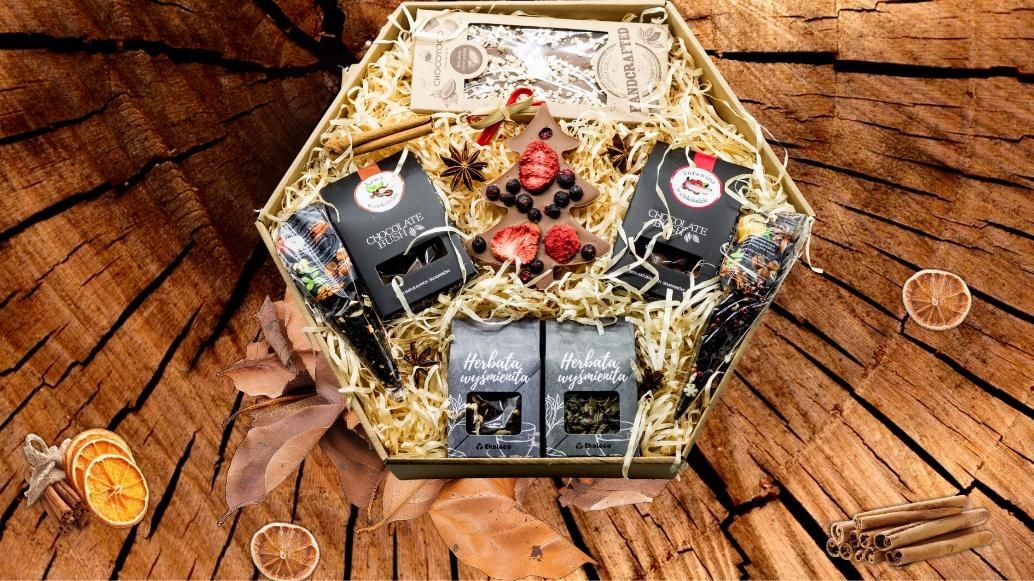 Zestaw prezentowy Q21 w pudełku plaster miodu – czekolady, herbaty, ozdoby świąteczne i naturalne dodatki na tle drewnianym.