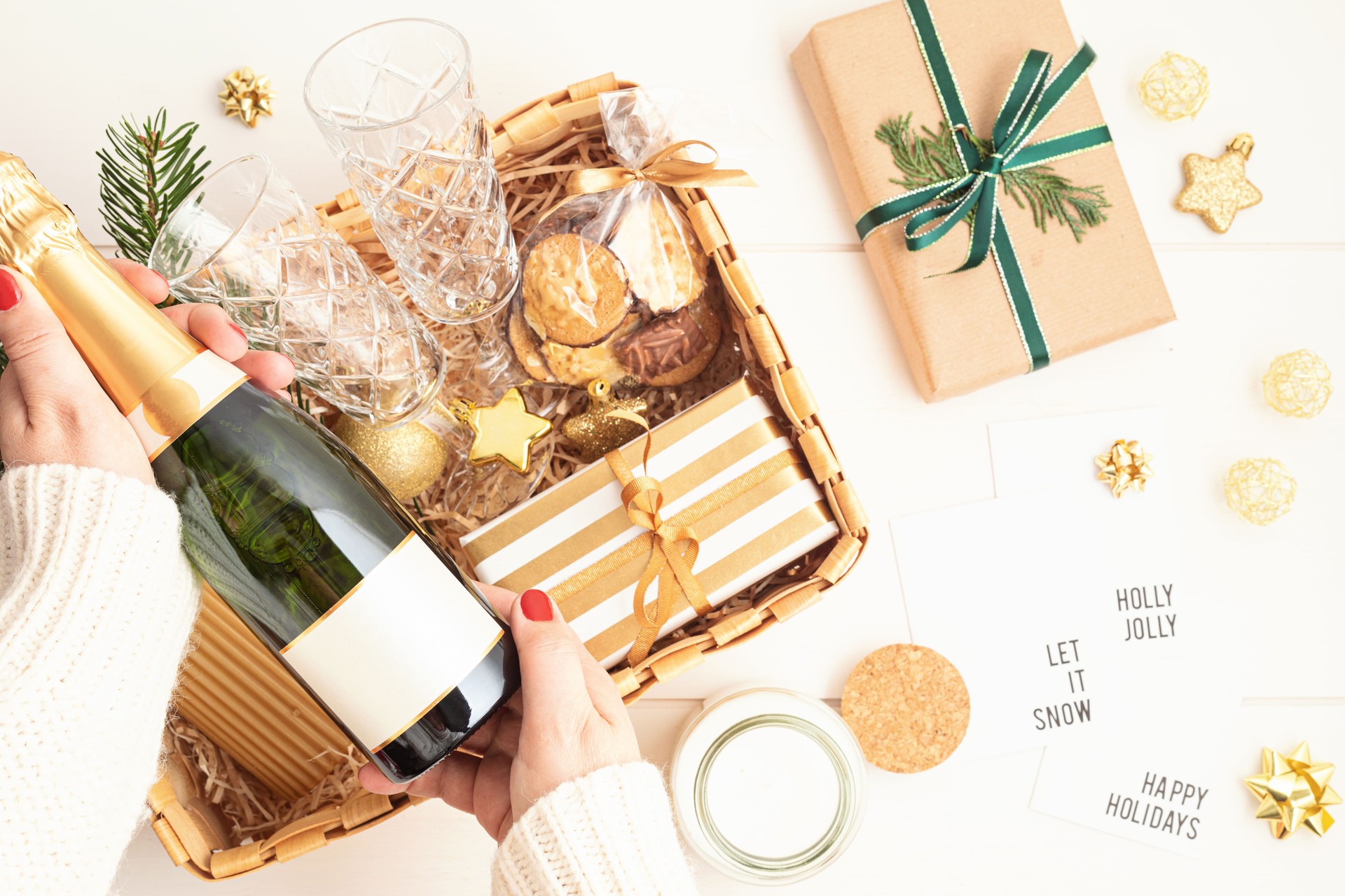 Refined Christmas gift basket for romantic holidays with bottle of champagne, wine glasses, cookies and candle